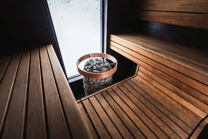 Un sauna confortable avec des bancs en bois et des pierres.